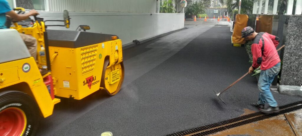 Jasa perbaikan jalan aspal di kawasan perkantoran.